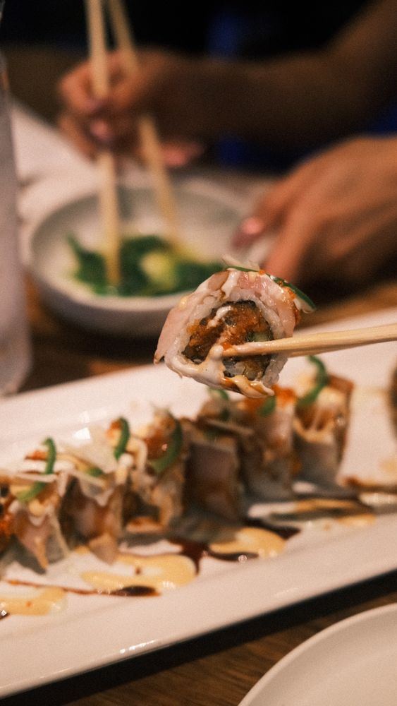 A piece of Guilty Pleasure roll held with chopsticks
